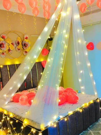 A beautiful canopy bed decoration with fairy lights and pink heart-shaped balloons. This setup is perfect for creating a soft and romantic atmosphere.