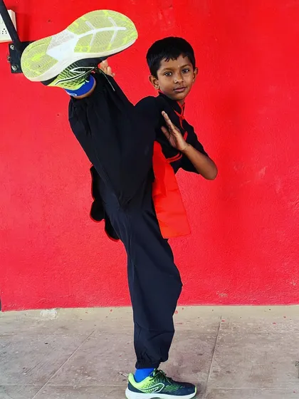 Discipline and flexibility start at any age. One of our young students demonstrates a controlled high kick, showing the physical conditioning and skill developed in our youth program.
