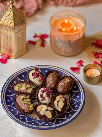 A selection of my chocolate-covered stuffed dates presented on a beautiful blue and white ceramic plate. This is an elegant and traditional treat, elevated with fine ingredients.