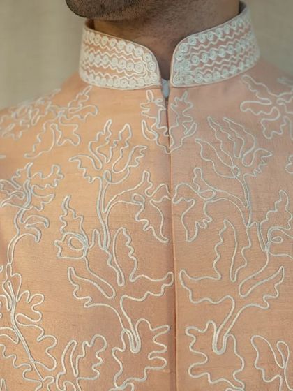 The delicate dori work on this peach silk jacket showcases a harmony of color and texture, creating a sophisticated and modern ethnic piece.