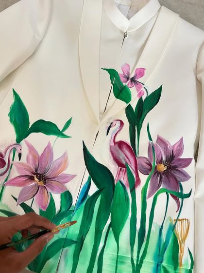 Adding the final touches to a tropical jacket. This scene includes purple lotuses and pink flamingos, creating a serene and beautiful waterside landscape.