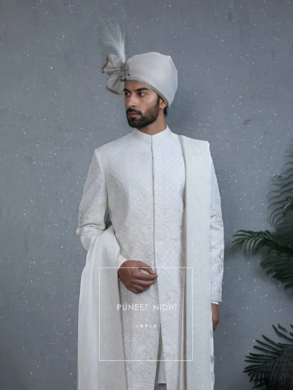 A creation where artistry meets royalty. This ivory sherwani features intricate embroidery and delicate beads, while the pleated stole drapes the timeless grace of tradition.