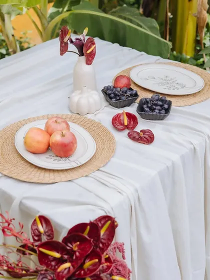 Another angle of the Orchard Table, showing the interplay of textures between the linen tablecloth, woven placemats, and fresh fruit.