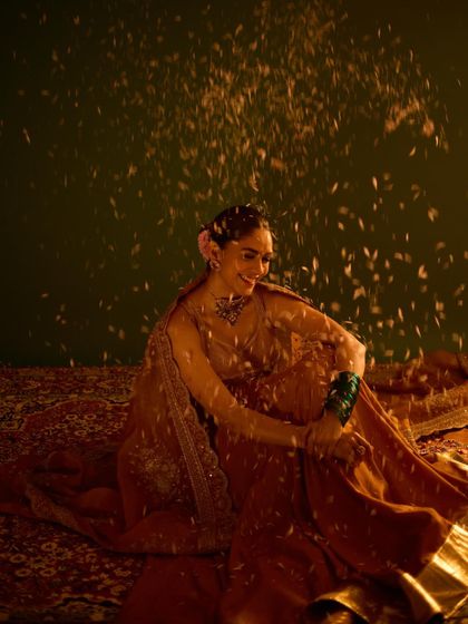 A magical shot of Mrunal Thakur in a custom golden anarkali, showered with flower petals for a festive Ganesh Chaturthi shoot.