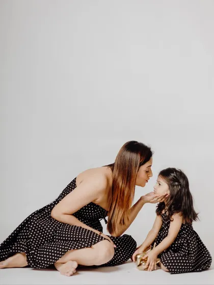 A tender moment between mother and daughter in matching polka-dot dresses. My studio's simple white background is perfect for creating clean, minimalist portraits that focus on emotion.