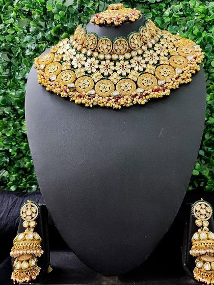 This rental set features a beautiful kundan choker with floral motifs and coin-like elements, paired with large, matching jhumkas.