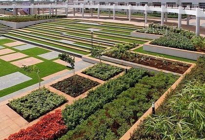 A closer view of the tiered planters and geometric grass sections in the podium garden. This type of landscape architecture requires precise execution.