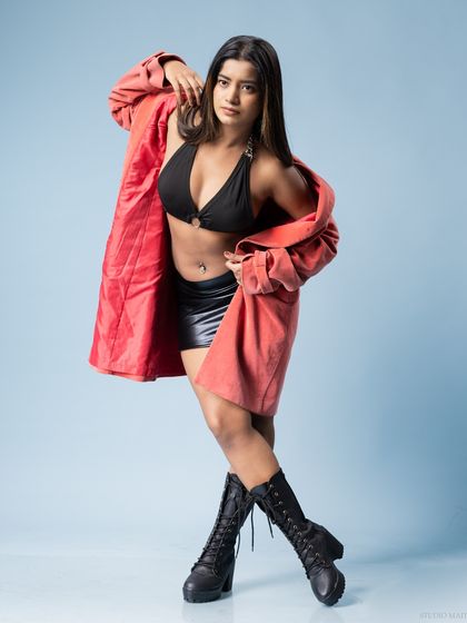 A full-body shot of the model in a black bikini, leather-look skirt, and red jacket, showcasing a confident and stylish pose. This is ideal for a fashion-forward model portfolio.