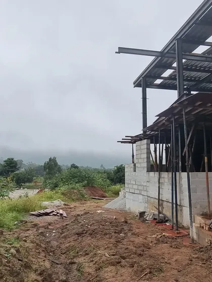 (Duplicate of 102) The raw, muddy ground and the skeletal structure of the house stand in contrast to the soft, misty landscape, capturing the reality of building in a natural environment.