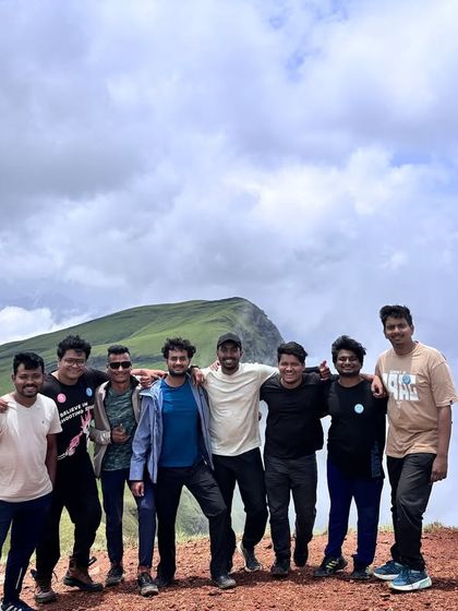 A group of trekkers on a mountain top, with arms around each other, enjoying the view. This is what our community is all about: shared moments and lasting friendships.