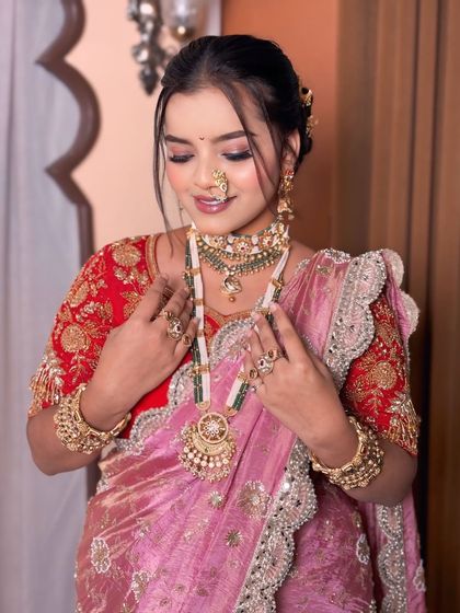 The bride looking down, showcasing her beautiful eye makeup and the heavy traditional necklace.