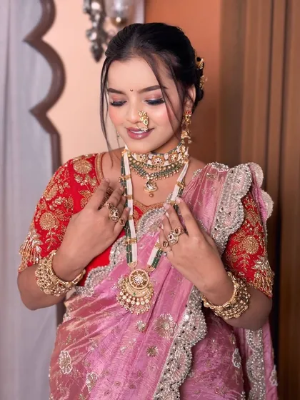 The bride looking down, showcasing her beautiful eye makeup and the heavy traditional necklace.