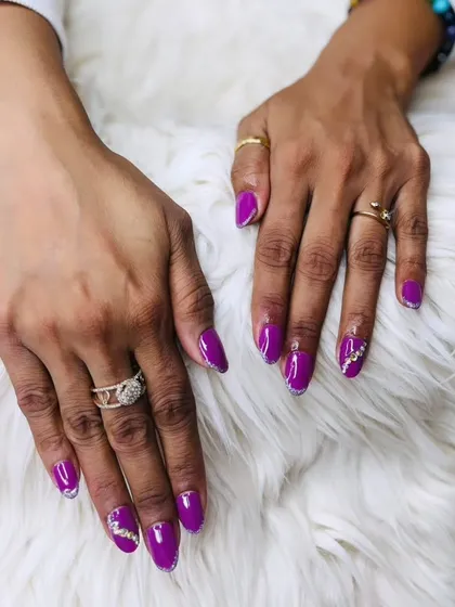 A striking set of purple gel extensions with silver glitter accents and intricate rhinestone patterns for a truly glamorous finish.