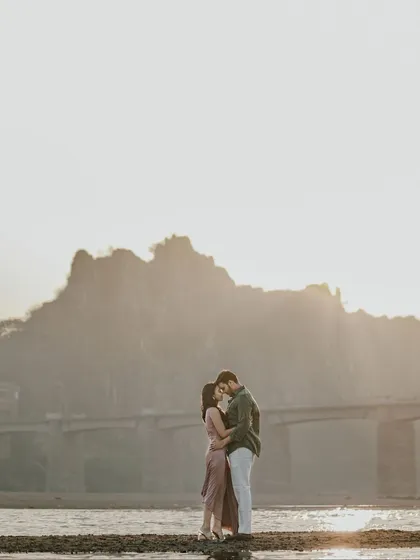 A close-up silhouette of the couple about to kiss, set against a hazy, sunlit landscape. This image is full of romance and anticipation, perfect for a coastal love story.