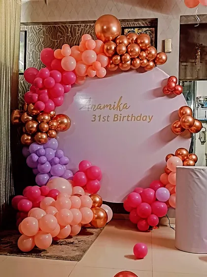 A colorful and chic decoration for a 31st birthday. This setup uses a custom backdrop panel and a balloon arch with a beautiful blend of pink, purple, and rose gold chrome balloons.