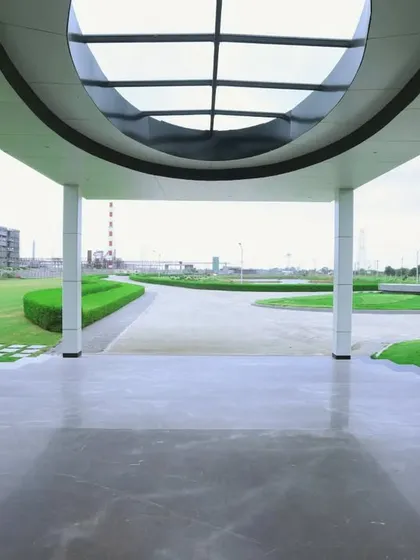 A view from beneath the entrance canopy, looking out onto the landscaped grounds. The polished marble floor reflects the sky, and the circular skylight adds a dramatic architectural detail.