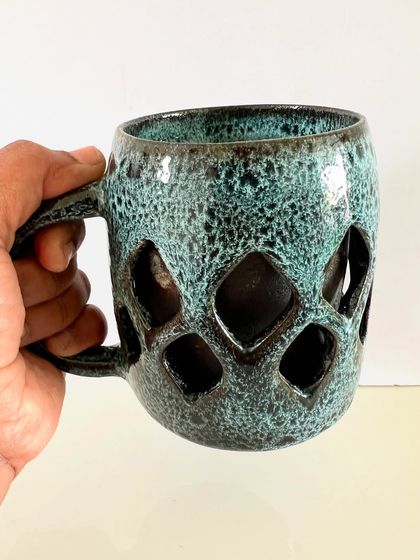 Holding the geometric double-walled mug to show its size and comfortable grip. This is a large mug, perfect for a generous serving of your favorite hot beverage.