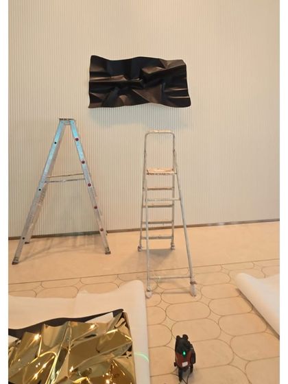 The installation process begins for a huge 13-foot sculpture. Here you can see one panel on the wall and another waiting on the floor.