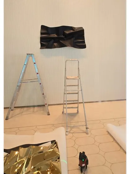 The installation process begins for a huge 13-foot sculpture. Here you can see one panel on the wall and another waiting on the floor.