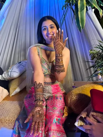 The bride shows off both her hands, covered in our signature intricate mehandi, ready for her wedding festivities.