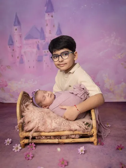 A proud big brother poses with his sleeping sister in their magical castle-themed shoot.