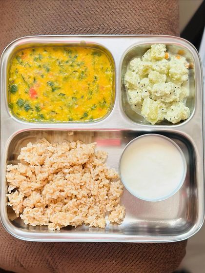 This light meal features broken wheat, dal palak, sautéed potato with poppy seeds, and a side of curd.