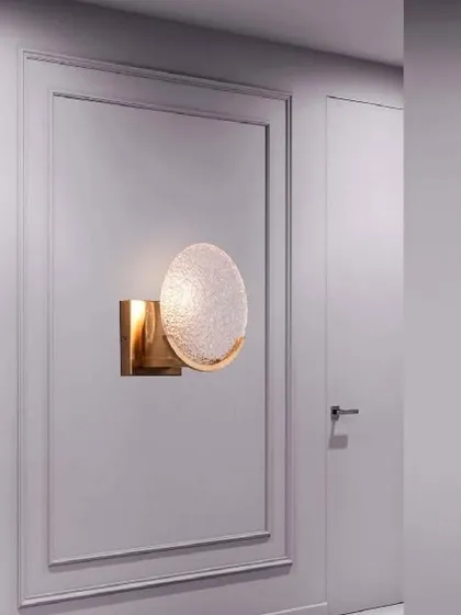 A dash of antique brass, this elliptical wall light features a textured, gleaming metal glass shade. The unique shape and warm glow create a sophisticated and artistic accent for a hallway or living room.