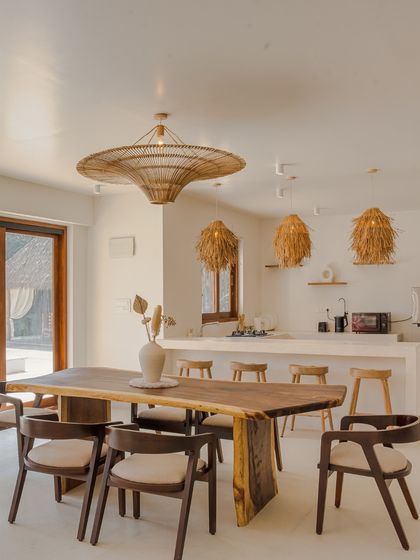The open-plan dining area and kitchen flow seamlessly from the living space. A live-edge wooden dining table is paired with modern chairs, all under beautiful woven light fixtures that tie the entire ground floor together.