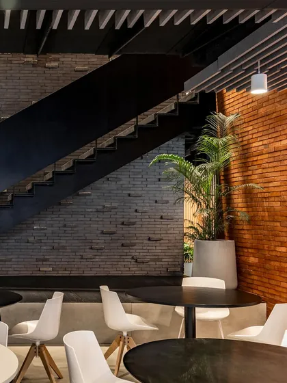The cafe area at BCG HQ combines various textures, from the smooth white chairs to the rough brick walls, creating a rich sensory experience in a communal space.