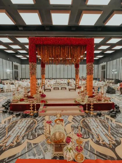 A frontal view of the grand, red-themed wedding mandap at the Fairmont Mumbai. The elevated platform, intricate floral work, and traditional brass lamps create a sacred and imposing space for the ceremony.
