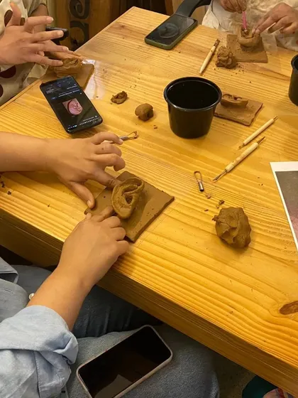 A top-down view of the sculpting process, with reference photos on phones guiding the artists. We encourage using all available resources to learn and improve your craft.