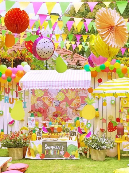 A "Tutti Frutti" birthday party bursting with color. The fruit stand backdrop, balloon garland, and fresh fruit displays created a healthy and vibrant theme.