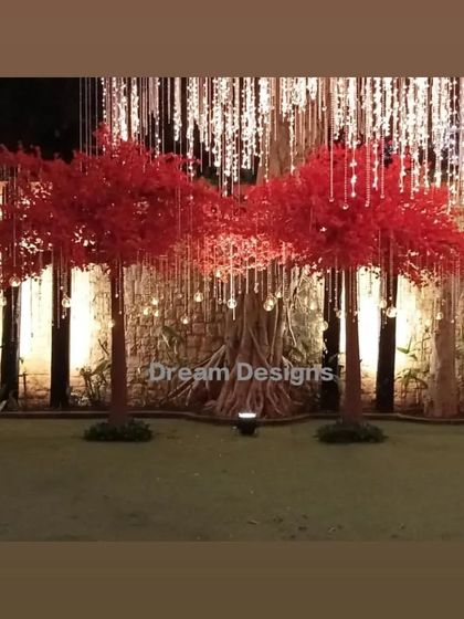 A beautiful installation of artificial red trees against a curtain of lights. This setup serves as a stunning backdrop or photo opportunity, tying into the red theme of the event.