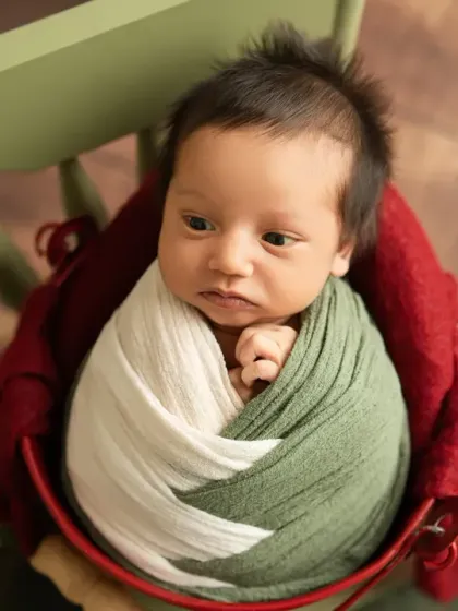 This alert baby is looking right at the camera, wrapped snugly in earthy green and white tones. It's always a special treat to capture their beautiful, open eyes.