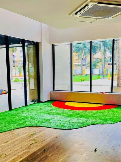 An indoor commercial space, possibly a daycare or play area, where we installed a custom-cut piece of turf with colorful inlays. Our products are safe for kids and can be shaped to any design.