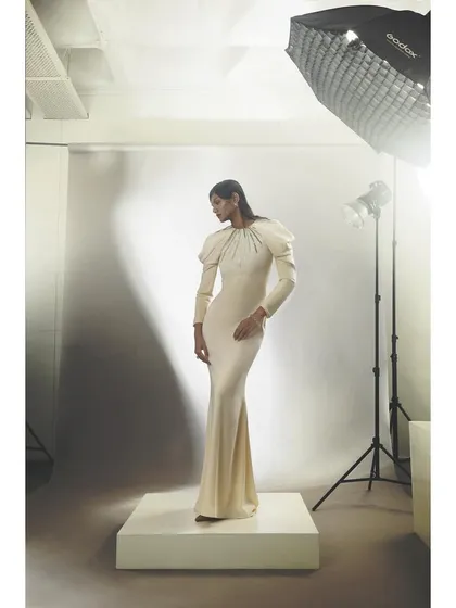 A behind-the-scenes view of the white long-sleeved gown. Showing the studio lights and setup provides context and demonstrates the technical side of a fashion shoot.