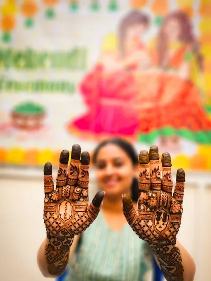 A fun shot with the bride and her mehendi ceremony banner in the background, capturing the happy atmosphere of the event.