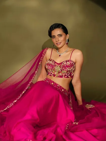A beautiful seated pose that showcases the intricate embroidery of the blouse and the complementary tones in the makeup.