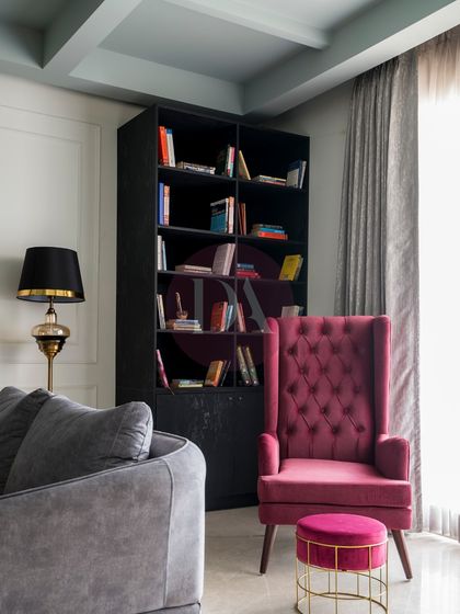 Another angle of the reading nook, emphasizing the contrast between the plush magenta armchair and the dark, stately bookshelf. A vintage-style floor lamp provides warm, focused light, making it the perfect spot to get lost in a book.