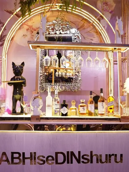 A close-up of the whimsical bar, showing the quirky bulldog statue holding a tray, set against the beautiful hand-painted floral backdrop.