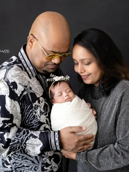 Mom and dad looking down at their sleeping baby. This image tells a beautiful story of love, protection, and the beginning of a new family journey.