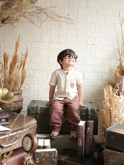 The birthday boy looks up with a dreamy expression, showcasing a candid, thoughtful moment captured during his styled session.