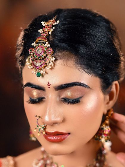 A detailed close-up of bridal makeup, showing the flawless base, shimmering eyeshadow, and intricate maang tikka. This is the kind of high-quality shot MUAs need for their portfolio.
