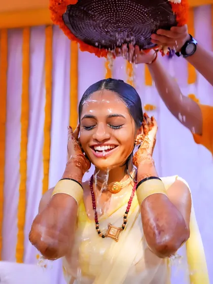 The sheer delight of a traditional Haldi ritual. This shot freezes a moment of pure happiness, with water splashing down and a smile that lights up the frame. We focus on capturing the energy and fun of your wedding ceremonies.