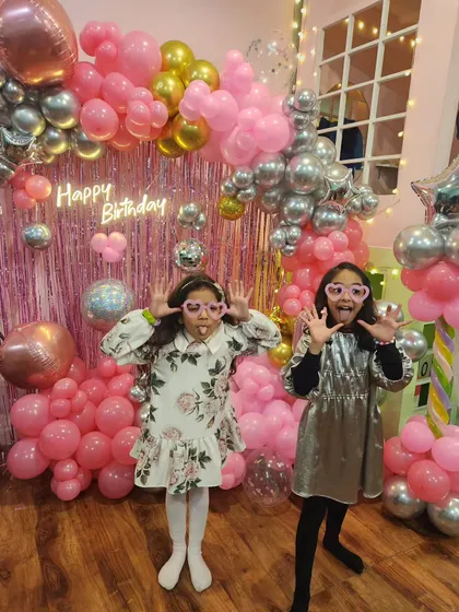 Getting ready to rock with a popstar-themed party. The backdrop is all about pink and silver, with shiny disco balls and a neon "Happy Birthday" sign.