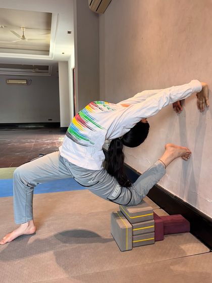 Using the wall and blocks for support, a student works on a deep lunge variation to open the hips for splits.