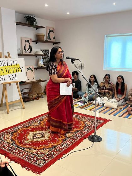 A performer in a beautiful saree commands the stage at our open mic. Our community is a vibrant mix of people from diverse backgrounds, united by their love for poetry.