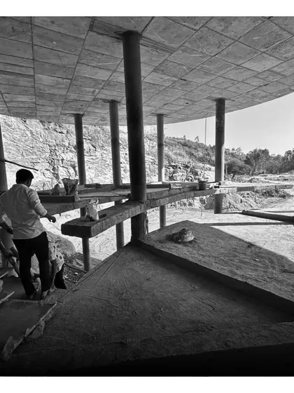 Workers on site, building the multi-level structure that seems to grow out of the rocky cliffside.