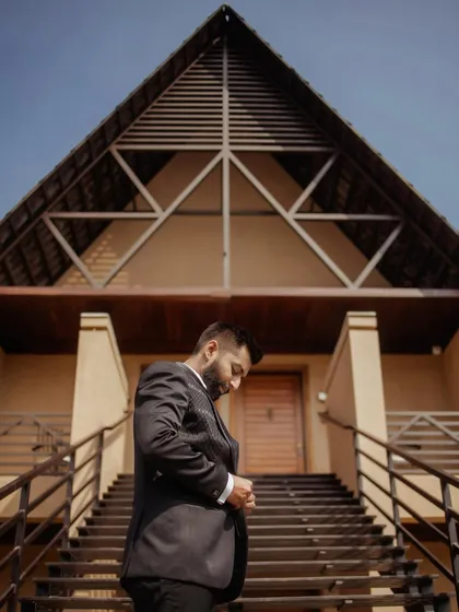 The groom, looking sharp in his suit, captured from a low angle against the modern architecture of the venue, creating a powerful and stylish portrait.