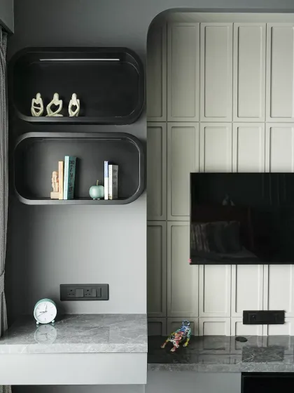 A seamless fusion of a study nook and TV unit, this sleek recessed shelving unit features smooth, curved edges and a deep matte black finish, creating a bold contrast against the muted gray wall.